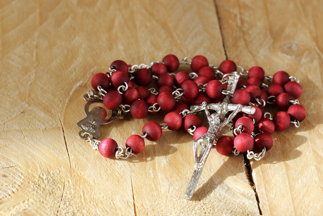 Red Rosary on wooden table